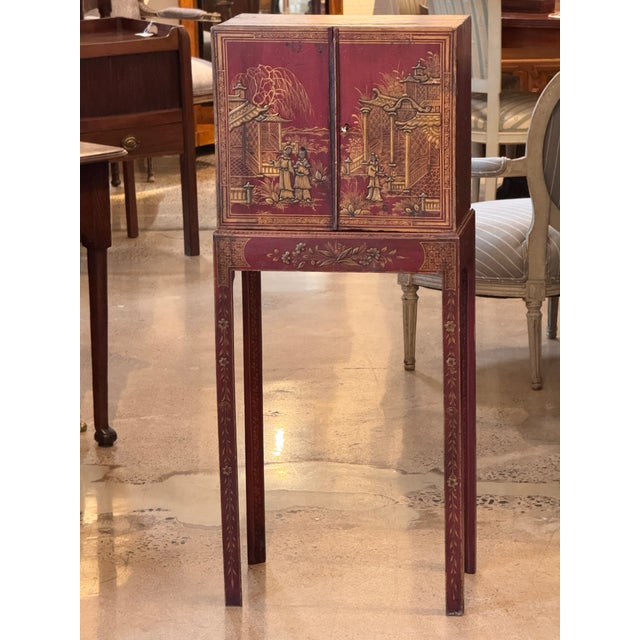Red painted chinoiserie cabinet on a matching stand, decorated throughout with gilt landscape scenes, figures, birds, and...
