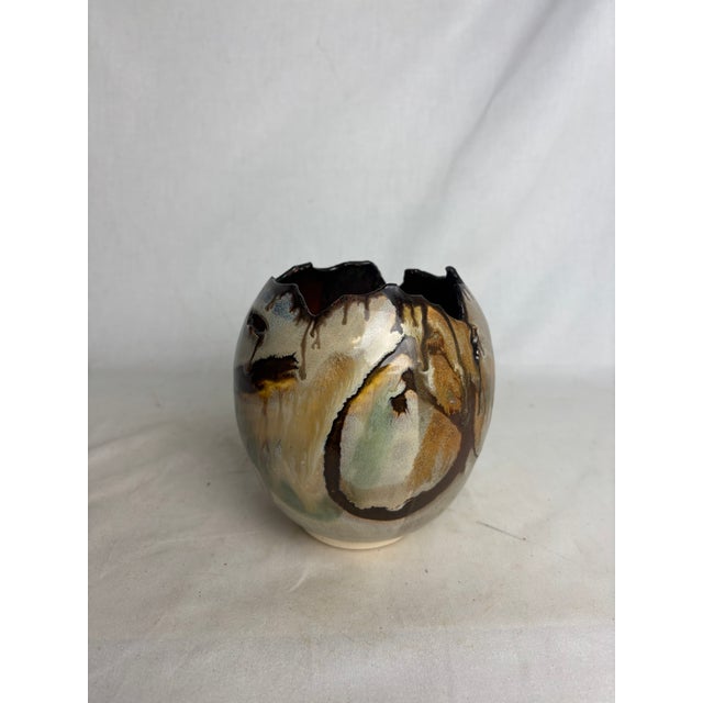 A gorgeous natural pottery vase in shades of rich, warm brown and accented by soft purples and greens. The deckled rim...