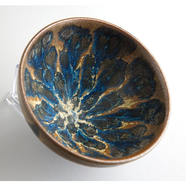 A striking Chinese stoneware tea bowl in the temmoku tradition, featuring a dramatic tortoiseshell glaze. The interior...