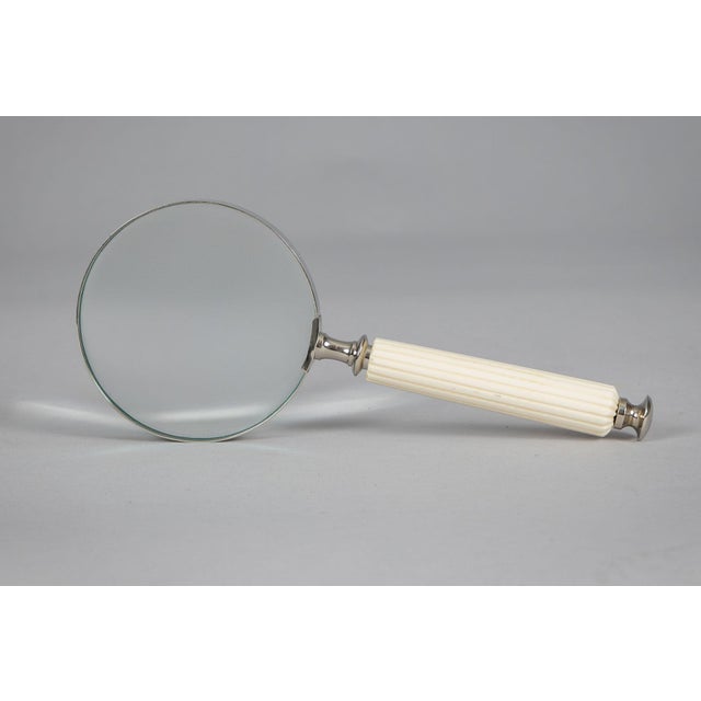 Large antique magnifying glass with carved and reeded off white tapered handle, metal frame, collar and finial.
