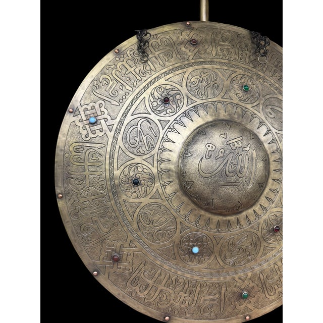 A handmade Turkish brass armor display featuring a domed helmet and round shield mounted on a matching pedestal stand....