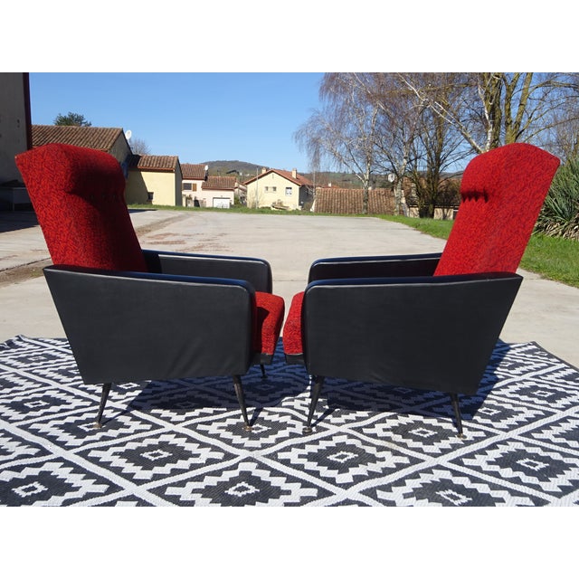 Red and black faux leather and fabric armchairs with splayed legs. Black faux leather armrests. Seat and back upholstered...