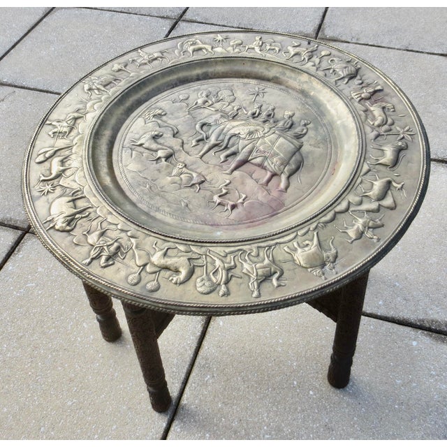 Anglo-Indian hammered brass/copper alloy tray table. The tray features an elaborate hunting scene of the Raja on an...