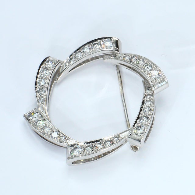 This circular brooch features a series of brilliant-cut diamonds set in a white gold frame. The diamonds are arranged in a...