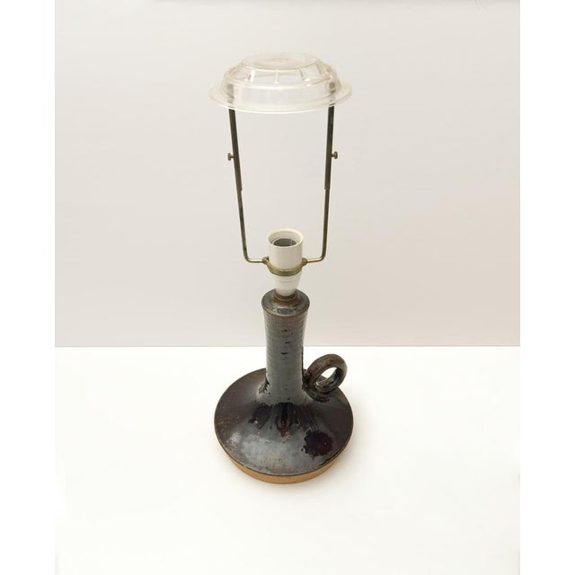A mid-century danish stoneware table lamp characterised by its sculptural form and richly textured brown glaze. The lamp...