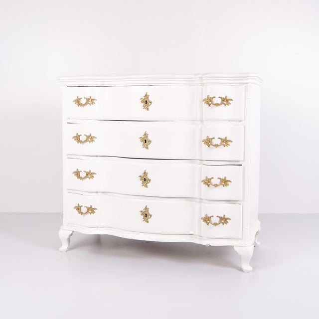 Antique baroque chest of drawers from the 1760s, painted white with brass handles. Four drawers and a distinctive baroque...