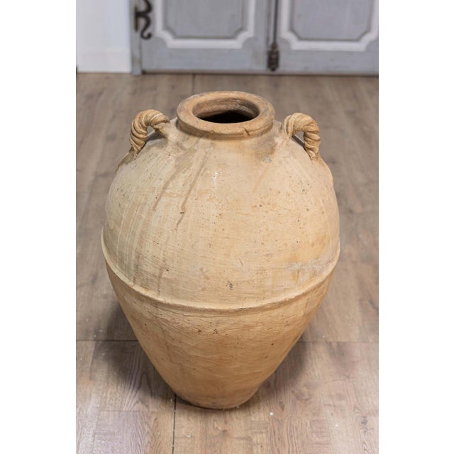 An early 19th century terracotta olive oil jar from Naples, Italy with twisted handles and rustic character. This early...