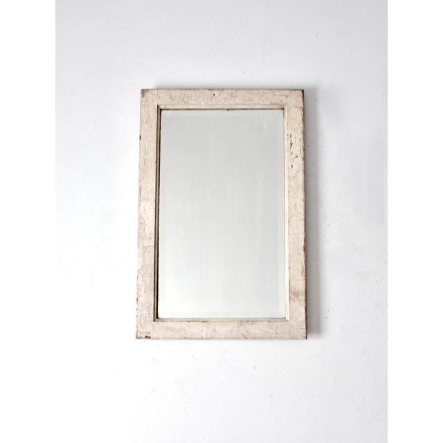 Antique wood frame mirror featuring beveled glass and a creamy white, crazed painted finish that creates a layered,...
