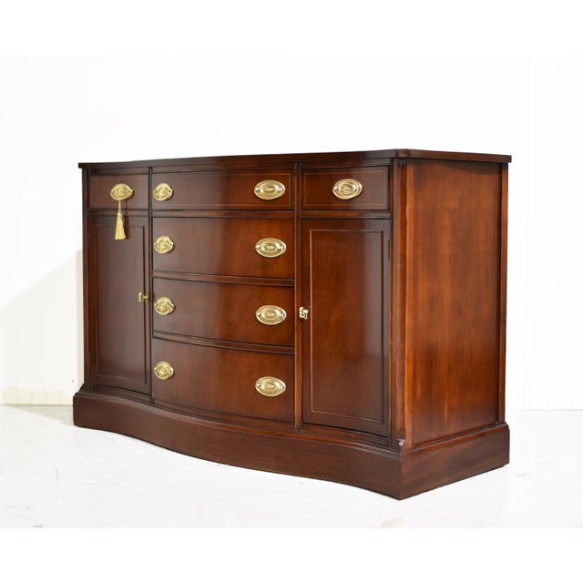 Stately and beautifully proportioned, this mid-century Federal style curve front buffet by Bassett Furniture is a...