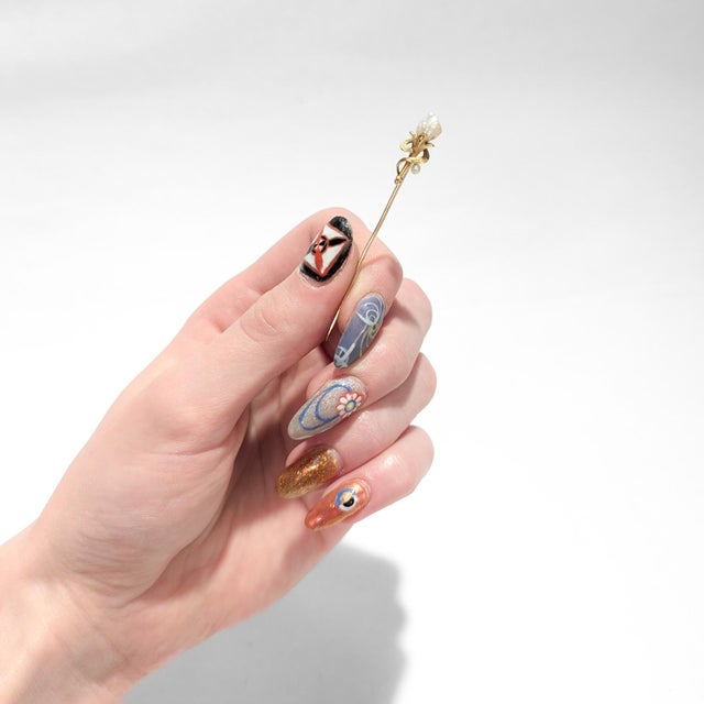 A fine signed Edwardian gold stickpin. In 14 karat yellow gold. In the form of a stylized flower with a blister pearl as...