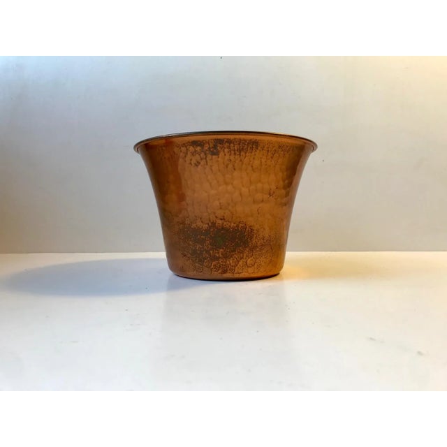 Ornate planter in solid copper. The hammering done to the planter mimics lizard skin. It was designed and manufactured by...