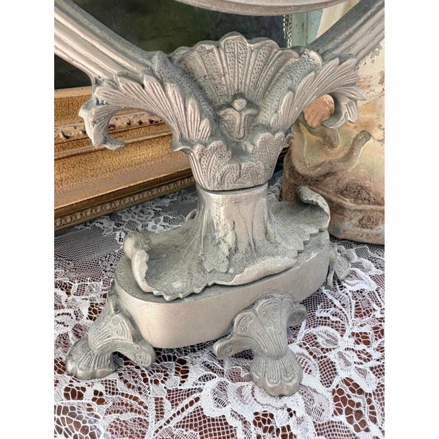 Beautiful vintage Hollywood Regency tabletop vanity mirror featuring an elaborate silver-tone cast metal frame adorned...