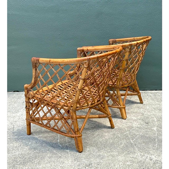 This exquisite pair of vintage rattan lounge chairs features a striking diamond-lattice or trellis design that...