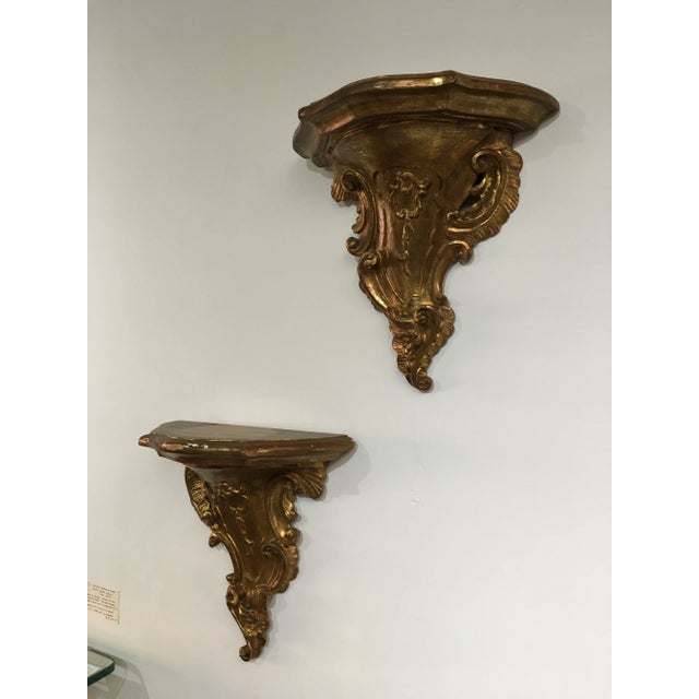 An exceptional pair of authentic 19th-century Italian Rococo wall shelves, masterfully hand-carved from solid wood and...