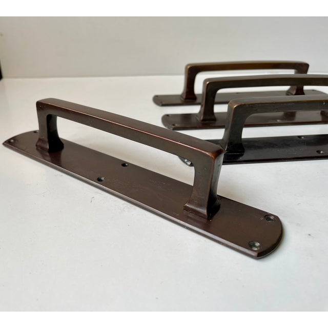 Two sets of patinated bronze gate or push-door handles that was salvaged from a Danish Bank called Andelsbanken during the...