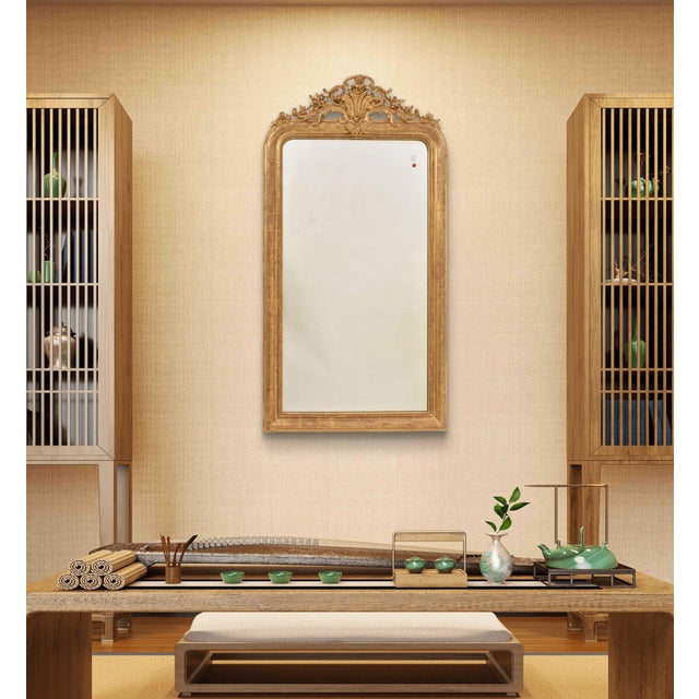 This elegant antique gilded mirror with floral crest, dating from the mid-19th century, features at the top a delicate...