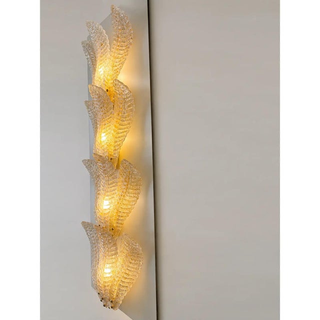 Contemporary luxury wall sconces in gold metal frame with leaves in murano glass and amber graniglia. a piece of hight...