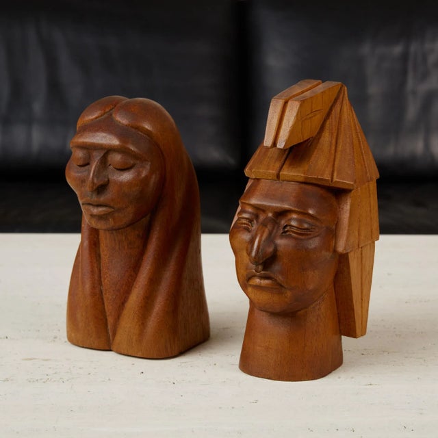 A complementary pair of male and female Native American, wooden busts by Jose Pinal, made in Mexico. One form highlights a...