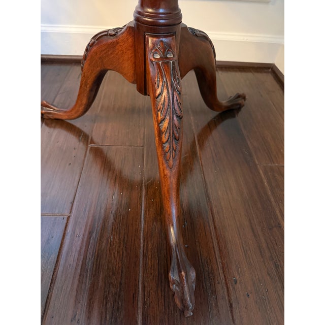 Add timeless elegance to your space with this classic Chippendale-style round pedestal accent table. Crafted from rich...