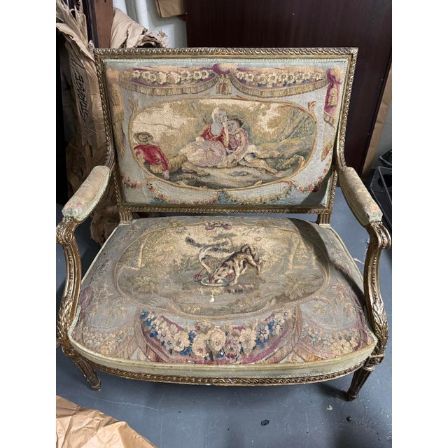 Antique French open armchairs in the Louis XVI manner, giltwood frames with rectangular backs, scroll-terminal open arms,...