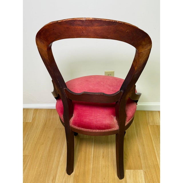 Antique Victorian-style balloon back parlor chair featuring a richly finished carved wood mahogany frame with graceful...