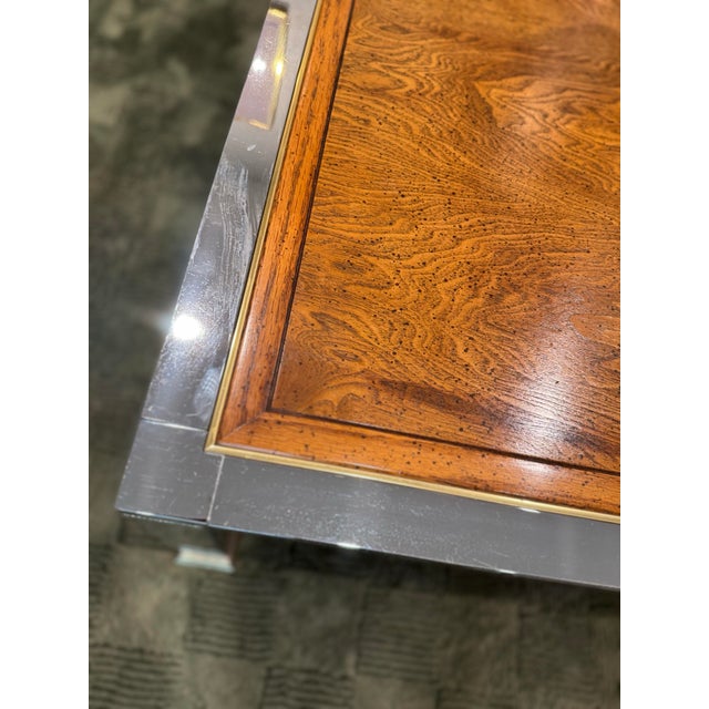 A beautiful mid century modern coffee table in the style of Milo Baughman, circa 1960s. Features a square burled olive...