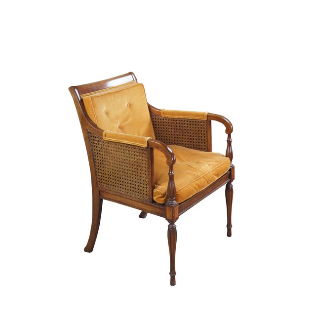 Two mid century French / Hollywood Regency style arm chairs. Made of walnut featuring a tufted back and fauteuil arms with...