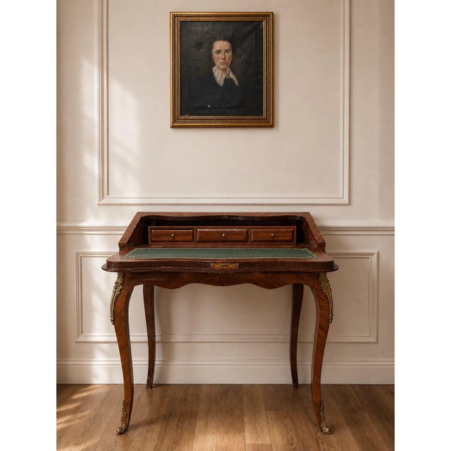 A beautifully detailed French Louis XV style writing desk featuring warm wood veneers, floral marquetry inlay, cabriole...
