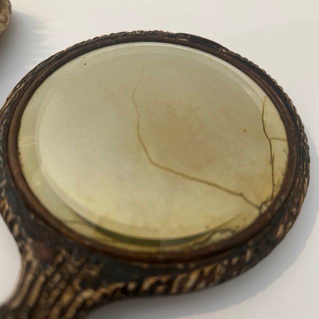 This three‑piece vintage vanity set includes a hand mirror, hairbrush, and powder brush, each featuring ornate faux antler...
