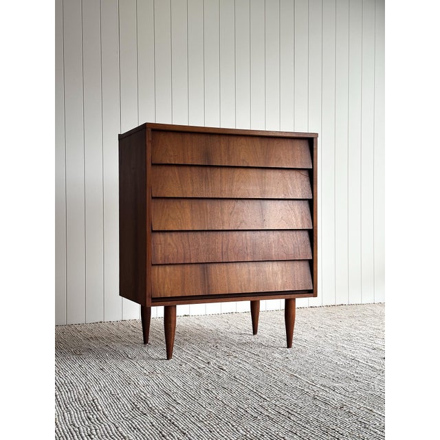 This vintage mid century five-drawer dresser features a clean architectural silhouette with stepped drawer fronts,...