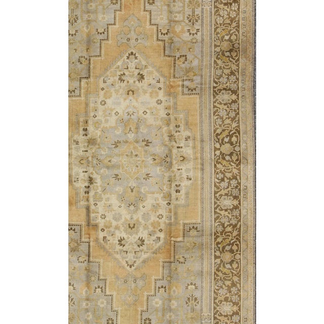 Measures: 6'8 x 12 This vintage Turkish Oushak features a bold design softened by unique, light tones. The border is...