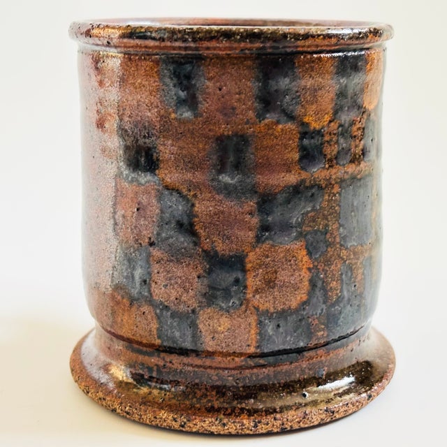 A vintage studio pottery mug. Two toned brown glaze with a checkered pattern to the front. Signed PK on the base.