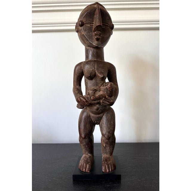 A finely carved Lwalwa maternity figure holding a baby from Democratic Republic of Congo in Central Africa circa 20th...
