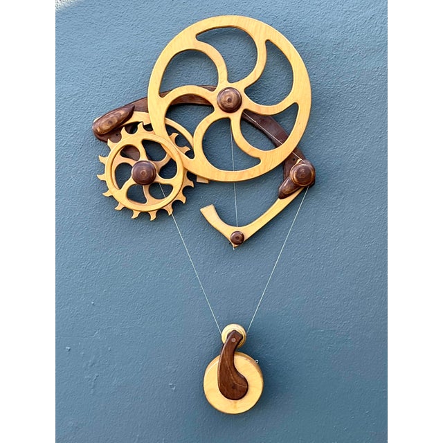 This captivating kinetic wall sculpture is a masterful fusion of industrial design and artisanal woodworking. Featuring a...