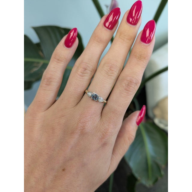 A natural color-change alexandrite sits at the centre of this solid two-tone 14K white and yellow gold ring, flanked by...