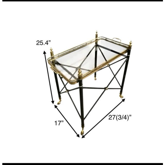 This item is a vintage Hollywood Regency style glass tray top side table featuring striking black and brass accents. This...