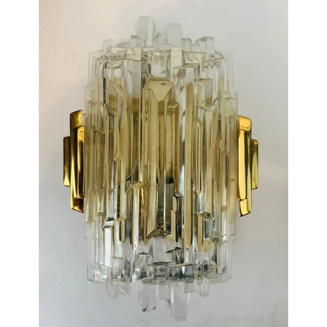 Pair of luxurious 1970s High Style wall lights composed of golden brass fittings and ice crystal glass shades. Newly...