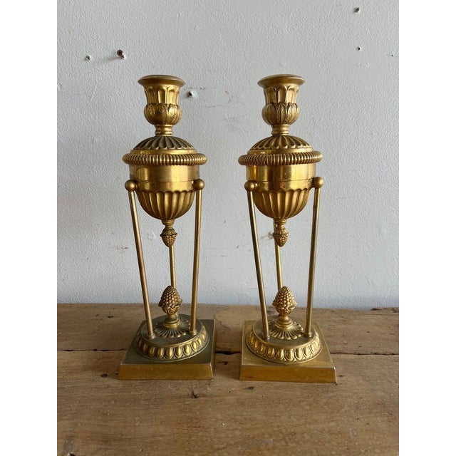 These candleholders are a pair of ornate classical style bronze pieces. They feature a design with a fluted top section...