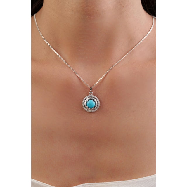This halo pendant features a 1.46 carat natural round turquoise, set in 14K white gold. The center stone measuring 8 mm in...