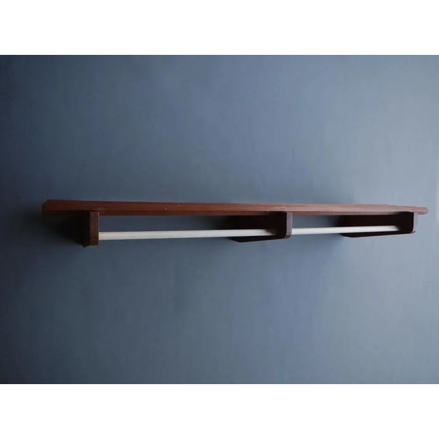 A teak wall-mounted clothes rack/hat stand.