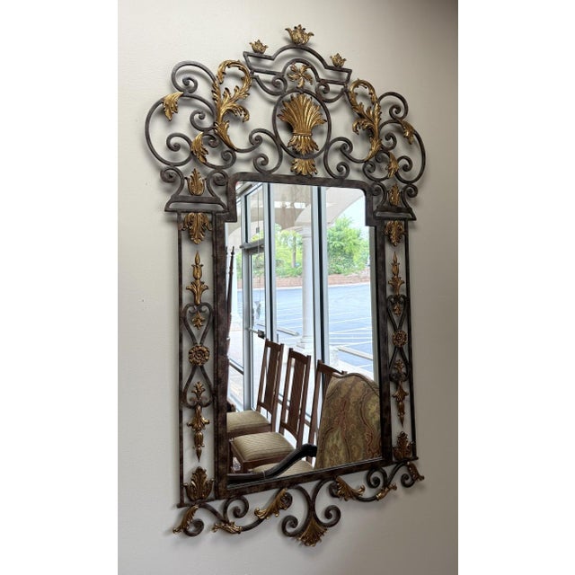 This impressive La Barge wall mirror features an elaborate wrought-iron frame with sweeping scrollwork, floral motifs, and...