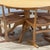 A refined mid-century dining set comprising a circular elm table and four matching rattan chairs, preserved in its...