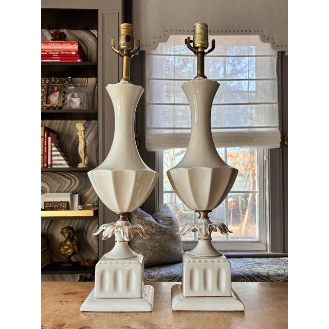 Pair of lovely porcelain Hollywood Regency table lamps with classic urn shape, scalloped details and gilded accents. 24”...