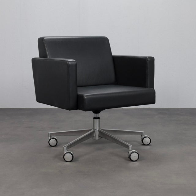 A refined pair of swivel armchairs by poltrona frau, expertly crafted in italy. Defined by their clean architectural lines...