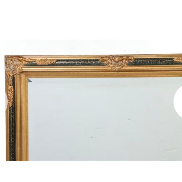 Elegant Regency Revival–style wall mirror featuring a richly detailed parcel-gilt wood frame with striking black lacquer...