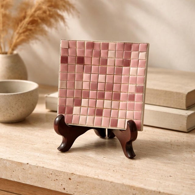 A charming blush-toned mosaic tile trivet featuring a grid of hand-set ceramic tiles in soft rose, mauve, and dusty pink...