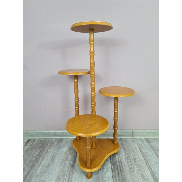 A decorative, multi-level flower stand made of wood in a warm, natural color. The structure consists of several round...