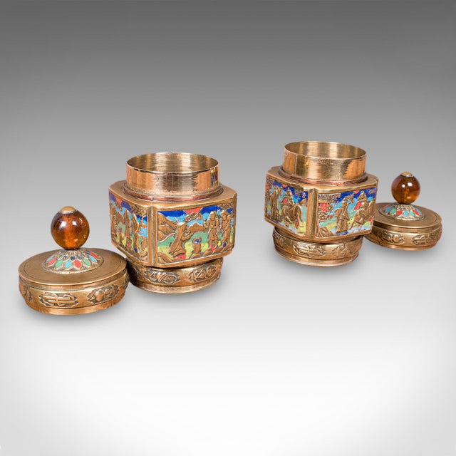 This is a pair of small Champlevé tea caddies. An Oriental, brass and enamel lidded spice pots, dating to the Edwardian...