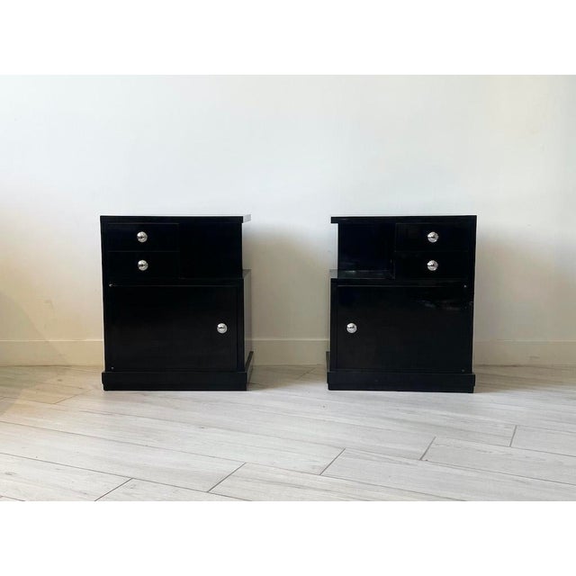 An elegant pair of bedside tables with a refined design, fully restored and featuring a glossy black lacquer finish,...