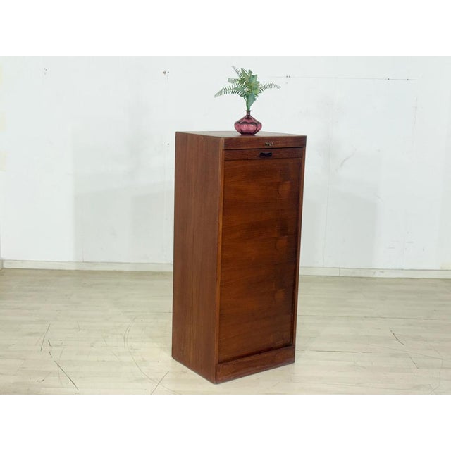High-quality vintage roll-top cabinet made of elegant teak. The cabinet features a striking slatted front and is in very...